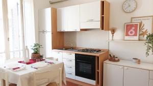 a kitchen with white cabinets and a table and a stove at Quick Home - Appartamento Narciso in Biella