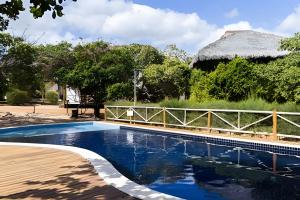 uma piscina com uma cerca e uma casa em Bangalô da Barra, chalé 20 - BG em Barra Grande