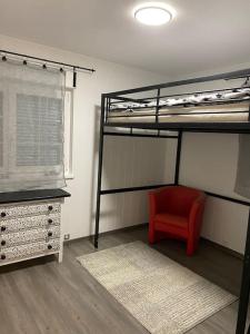 a bedroom with two bunk beds and a red chair at Appartement calme avec jardin in Conthey