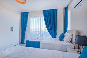 a bedroom with two beds and a window with blue curtains at Villa Simge 4+1 Ölüdeniz in Fethiye +18 photos