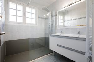 Baño blanco con lavabo y espejo en Grand Chalet St-Lary centre 13 à 15 pers, en Saint-Lary-Soulan