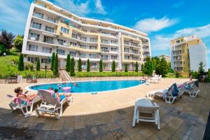 a group of people sitting in chairs by a swimming pool at Imperial and Crown Fort Noks Grand Resort in Sveti Vlas