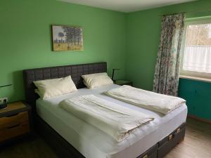 a bedroom with a bed with green walls and a window at Hotel Kienberger Hof in Pfronten