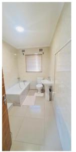 a bathroom with a toilet and a tub and a sink at Beautiful 3-Bed House in Harare in Harare