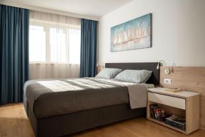 a bedroom with a large bed with blue curtains at Apartment Garden Palace B228 in Umag +30 photos