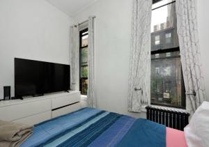 a white bedroom with a television and a bed at Designer 2BD 1BA In Upper East side in New York