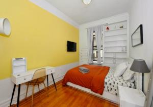 um quarto com uma secretária, uma cama e paredes amarelas em Designer 2BD 1BA In Upper East side em Nova York