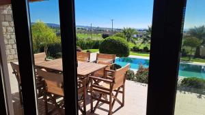 un tavolo e sedie in legno su un patio con piscina di Chrystallia Holiday Villas ad Anarita