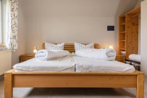 Una cama con sábanas blancas y almohadas. en 50141 Gretchen´s Hus 1, en Wangerland