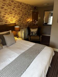 a bedroom with a large white bed and a chair at The Cricketers Arms in Barnard Castle