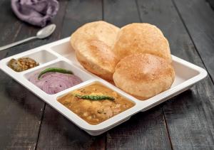 a tray of buns and dipping sauce and bread at Hotel Global Radiance Stay Near Delhi Airport in New Delhi