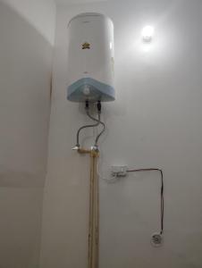 uma luz no canto de uma parede branca com um chuveiro em Ram Tilak homestay em Faizābād