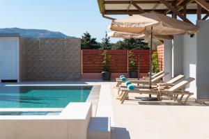 a swimming pool with two chairs and an umbrella at Elias' Rest in Pastida