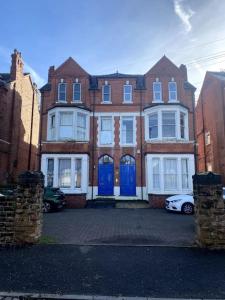 une grande maison en briques avec des portes bleues dans une rue dans l'établissement Huge Flat Sleeps 6+ free parking, à Nottingham