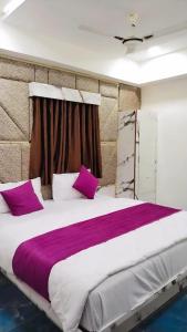 um quarto com uma cama grande com almofadas roxas e brancas em Hotel Karnavati em Ahmedabad
