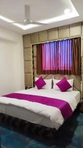 アーメダバードにあるHotel Karnavatiのベッドルーム1室(大型ベッド1台、紫色の枕付)