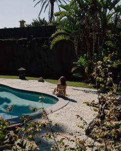 a little girl sitting on the sand next to a pool at Finca Tomaren in San Bartolomé