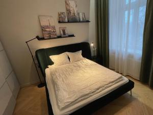 uma cama com um edredão branco num quarto em Cozy place on the left bank em Riga