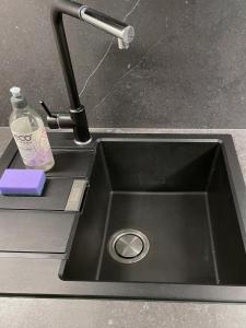 a kitchen sink with a bottle of detergent next to it at Cozy place on the left bank in Rīga
