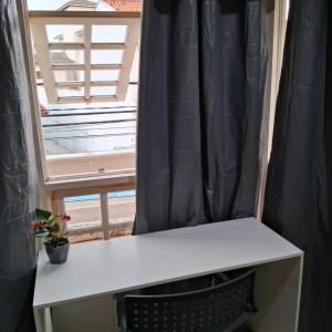 einen Schreibtisch vor einem Fenster mit einer Pflanze in der Unterkunft dormitorio 01 privativo a 2 km de alphaville in Barueri