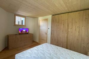 a bedroom with a bed and a flat screen tv at Chalet immerso nel verde in Madesimo