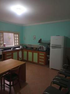 eine Küche mit einem Tisch und einem weißen Kühlschrank in der Unterkunft dormitorio 01 privativo a 2 km de alphaville in Barueri