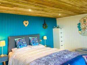 1 dormitorio con cama y pared azul en The Pod & Cwtch luxury accommodation en Aberaeron