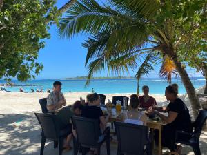 Ocean Cottage Maldives في ثولوسدو: مجموعة من الناس يجلسون على طاولة على الشاطئ