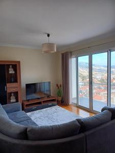 uma sala de estar com um sofá e uma televisão de ecrã plano em Ocean Paradise Til II no Funchal