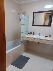 uma casa de banho com um lavatório, uma banheira e um espelho. em Ocean Paradise Til II no Funchal