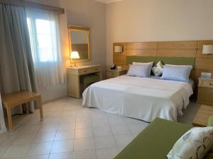 um quarto com uma grande cama branca e um espelho em Irene Villas em Arillas