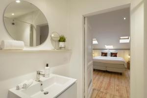 uma casa de banho com um lavatório, um espelho e uma cama em Our Bird's Nest in the Heart of Antwerp em Antuérpia