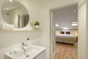 un bagno con lavandino, specchio e letto di Our Bird's Nest in the Heart of Antwerp ad Anversa