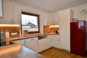 uma cozinha com armários brancos e um frigorífico vermelho em Ferienhaus Tirol im Ötztal em Umhausen