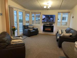 a living room with couches and a tv and a fireplace at Luxurious Beach Resort & Golf Club in Hunstanton