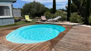 a pool on a wooden deck with chairs and a table at Chambre Pivoine au Domaine de l'Aven in Villeneuve-Minervois