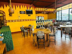 a restaurant with tables and chairs and a yellow wall at Arusha Backpackers Hotel in Arusha