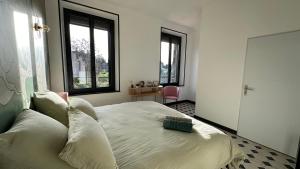 a bedroom with a bed and two windows at Chambre Pivoine au Domaine de l'Aven in Villeneuve-Minervois