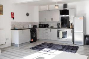 a kitchen with white cabinets and a refrigerator at Apartment 4 - 2 bed sleep 4, Prenton in Birkenhead