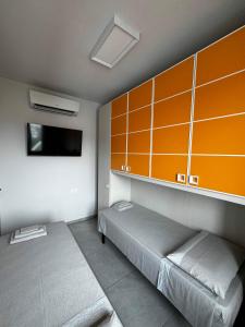 a bedroom with a bed and a wall with orange cabinets at Suite Nazioni in Lido delle Nazioni