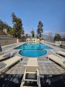 a large swimming pool with blue water and chairs at Ranikheth Ecostay in Kalimpong