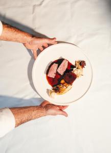 a person holding a plate of food on a bed at Biohotel Alte Post in Müllheim