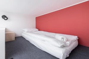 a bedroom with a bed with a red wall at Starowiślna Studio Kazimierz Cracow by Renters in Krakow