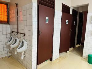 Baño con 3 urinarios en la pared en Arusha Backpackers Hotel, en Arusha