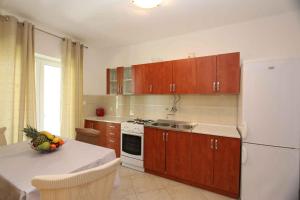 a kitchen with a white refrigerator and a table with a bowl of fruit at Apartment in Silo/Insel Krk 13564 in Šilo