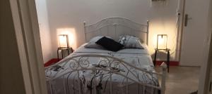 um quarto com uma cama branca e 2 candeeiros em Kaz à joss em Basse-Pointe