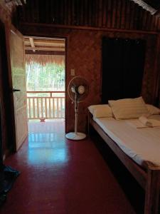 a bedroom with a bed with a fan and a window at Zhaya's Beach & Cottages in El Nido
