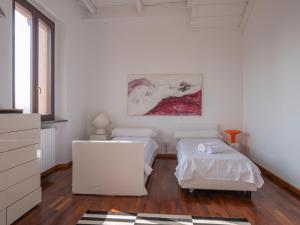 Habitación blanca con 2 camas y una pintura en la pared. en Cascina Torriggio Estates, en Rozzano