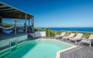 uma piscina com cadeiras e o oceano ao fundo em Luxury Vacation Villa 19 em Marigot