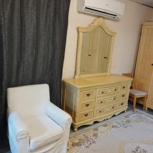 um quarto com uma cómoda, uma cadeira e um espelho em العين الهيلي مصباح ب1 em Al Ain